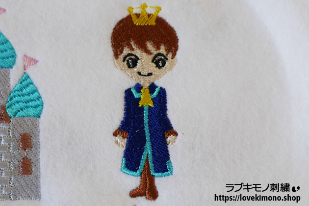 茶色のブーツ、青い服、黄色の王冠の王子様の刺繍